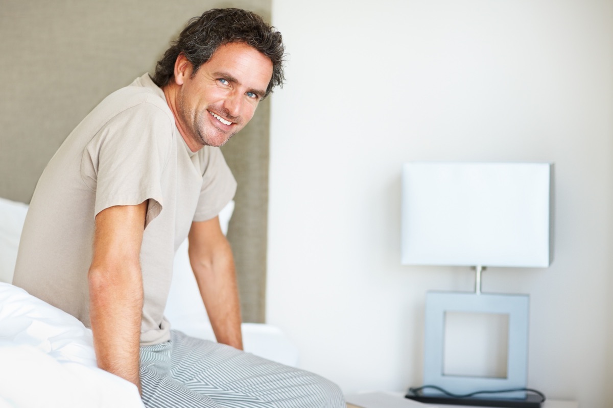man laying on a bed smiling at the camera